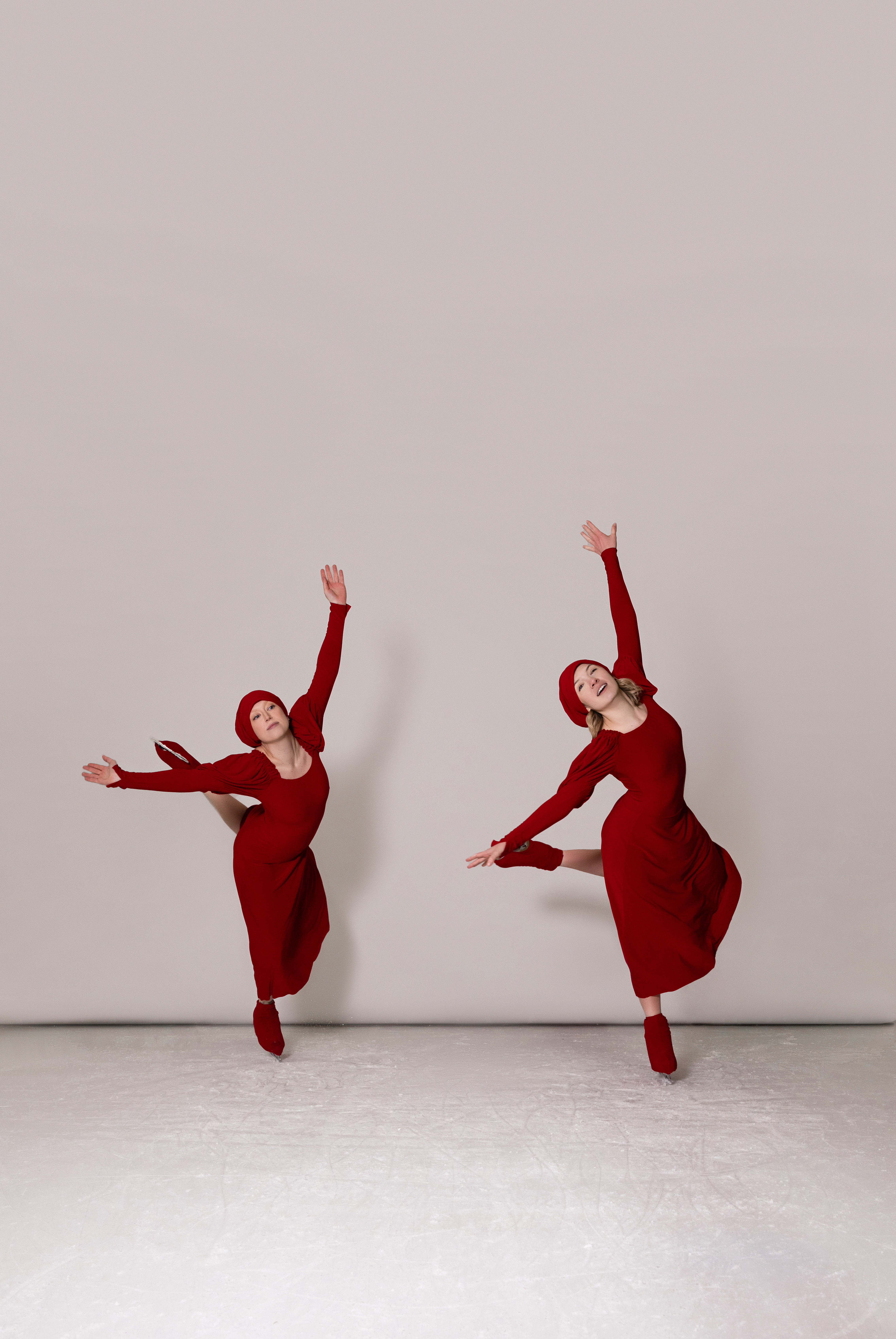 Two skaters in red, arms extended in mirrored positions